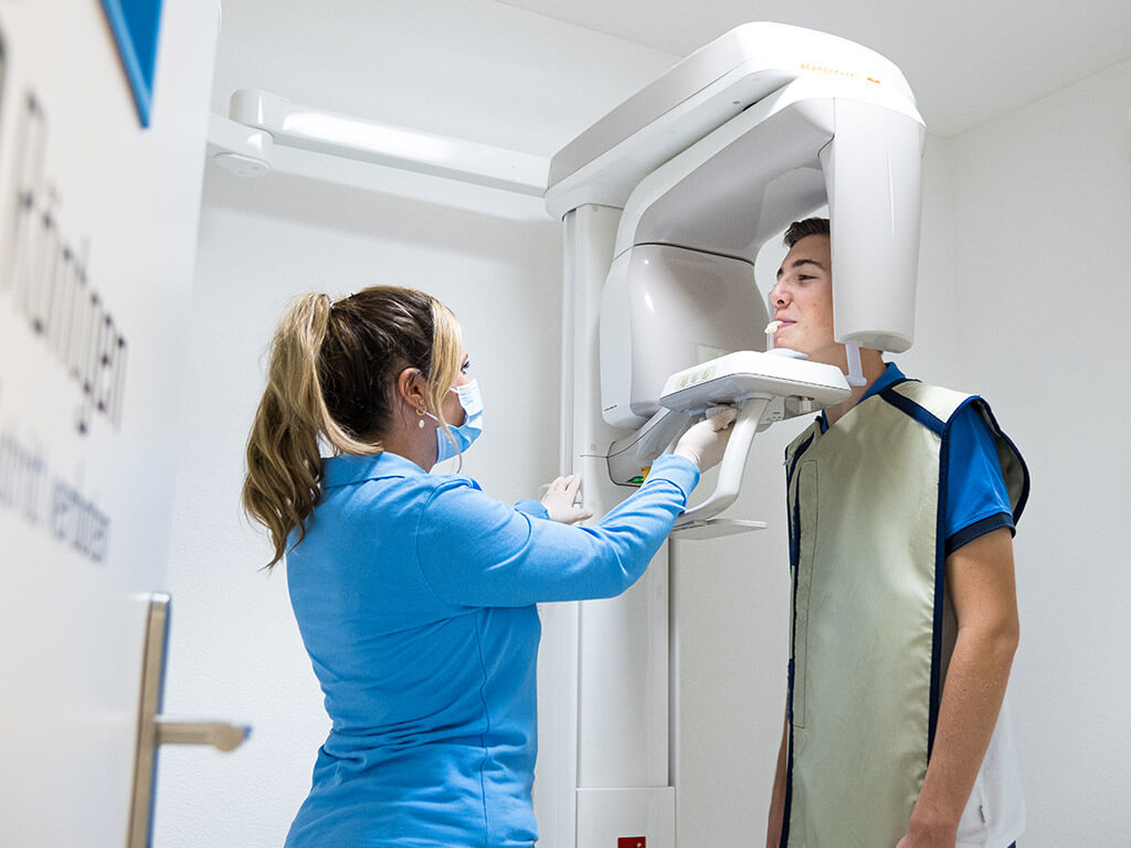 Patient wird am Röntgengerät von einer Mitarbeiterin geröngt.