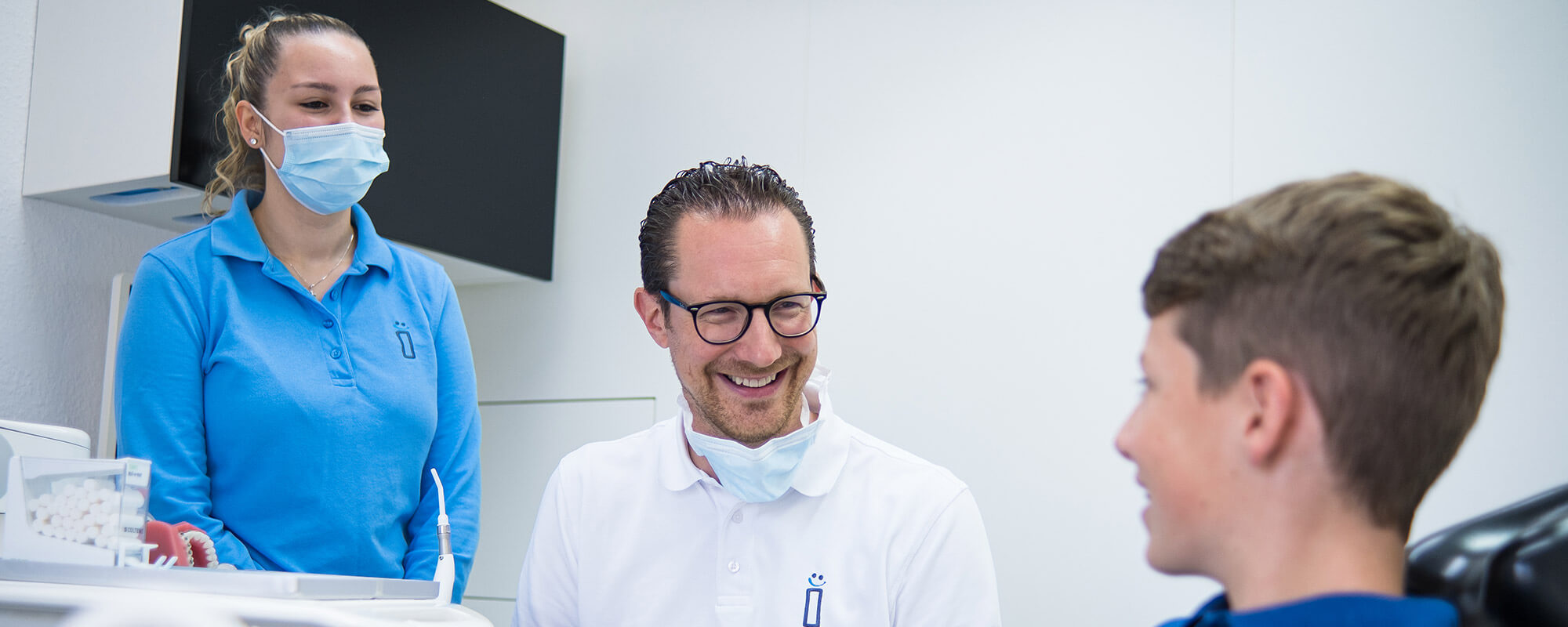 Dr. Plöger und eine Assistentin im Beratungsgespräch mit einem Jugendlichen.