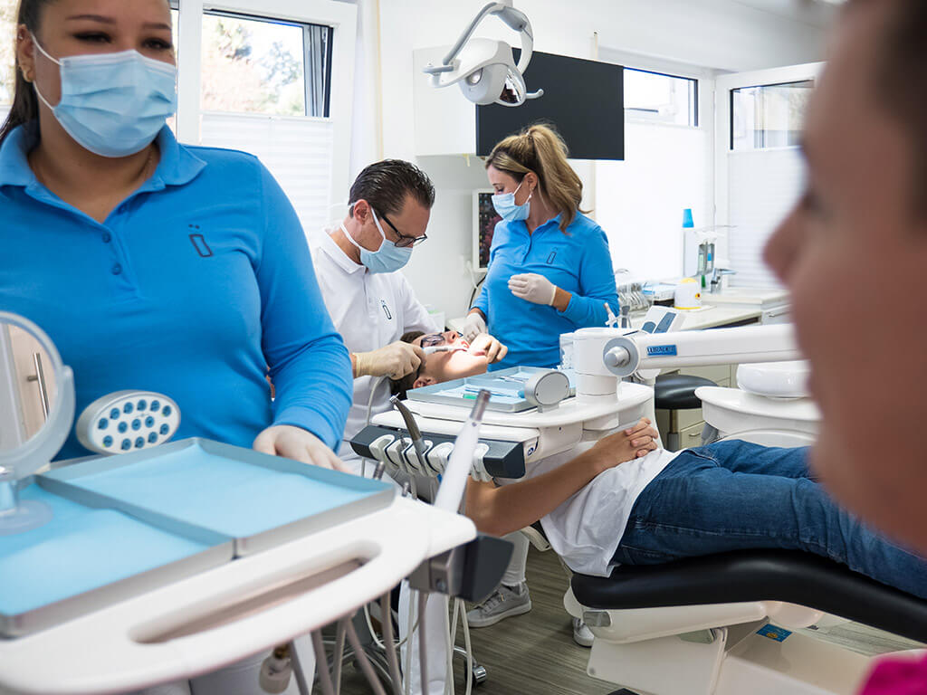 Behandlungsszene Dr. Plöger, Assistenz und junger Patient.